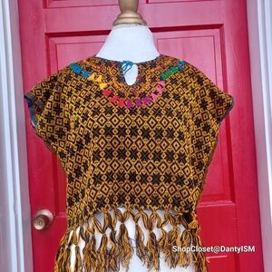 Handwoven Mexican Huipil with colorful embroidery and a fringed hem